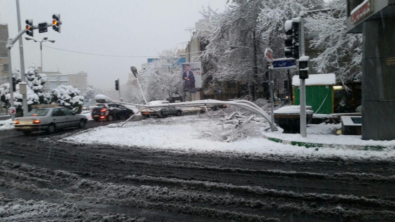 خم شدن تیرک&zwnj; چراغ برق بر اثر بارش شدید برف در تهران (عکس)